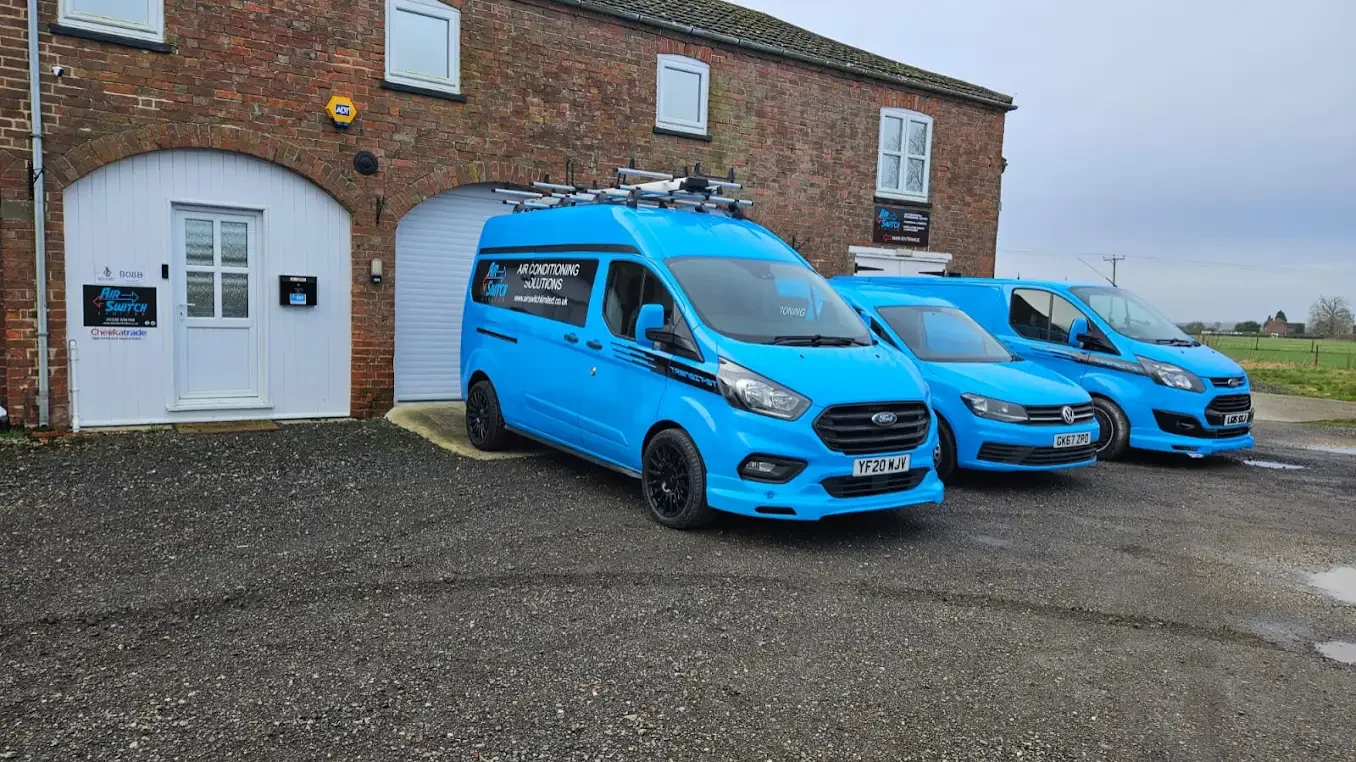 Air-Switch Offices in Moorby Three blue Air-Switch vans parked outside a brick building with white windows and doors.