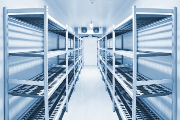 Large refrigerated trailer Empty metal shelving units in a large mobile refrigerated trailer unit with L.E.D lighting.