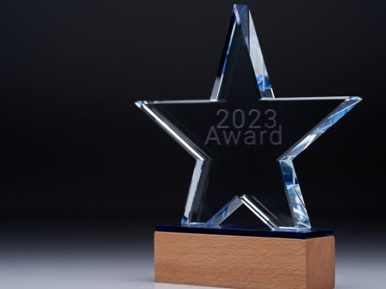 We are an award winning service Clear star-shaped award with "2023 Award" engraved, resting on a wooden base.