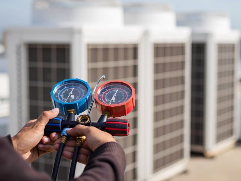 We offer a wide range of HVAC services Hand holding pressure gauges in front of industrial air conditioning units.