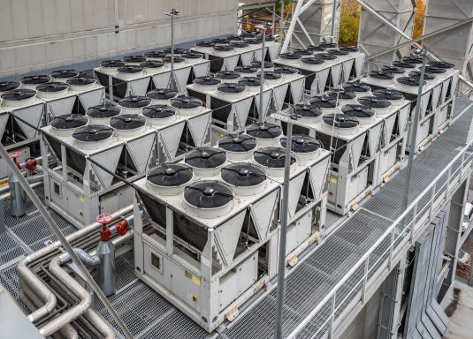 Rooftop chiller deck supplying chilled water equipment Roof-mounted industrial chiller units arranged in rows.