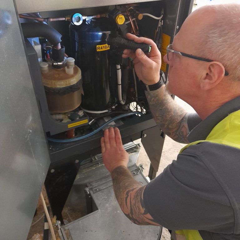Martin V. A technician inspects equipment inside a machine, focusing on its components.