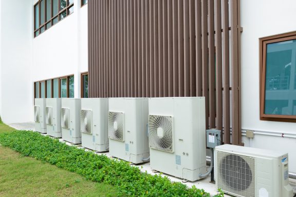 Large scale domestic installations Row of external air source heat pump units and single air conditioning condenser unit